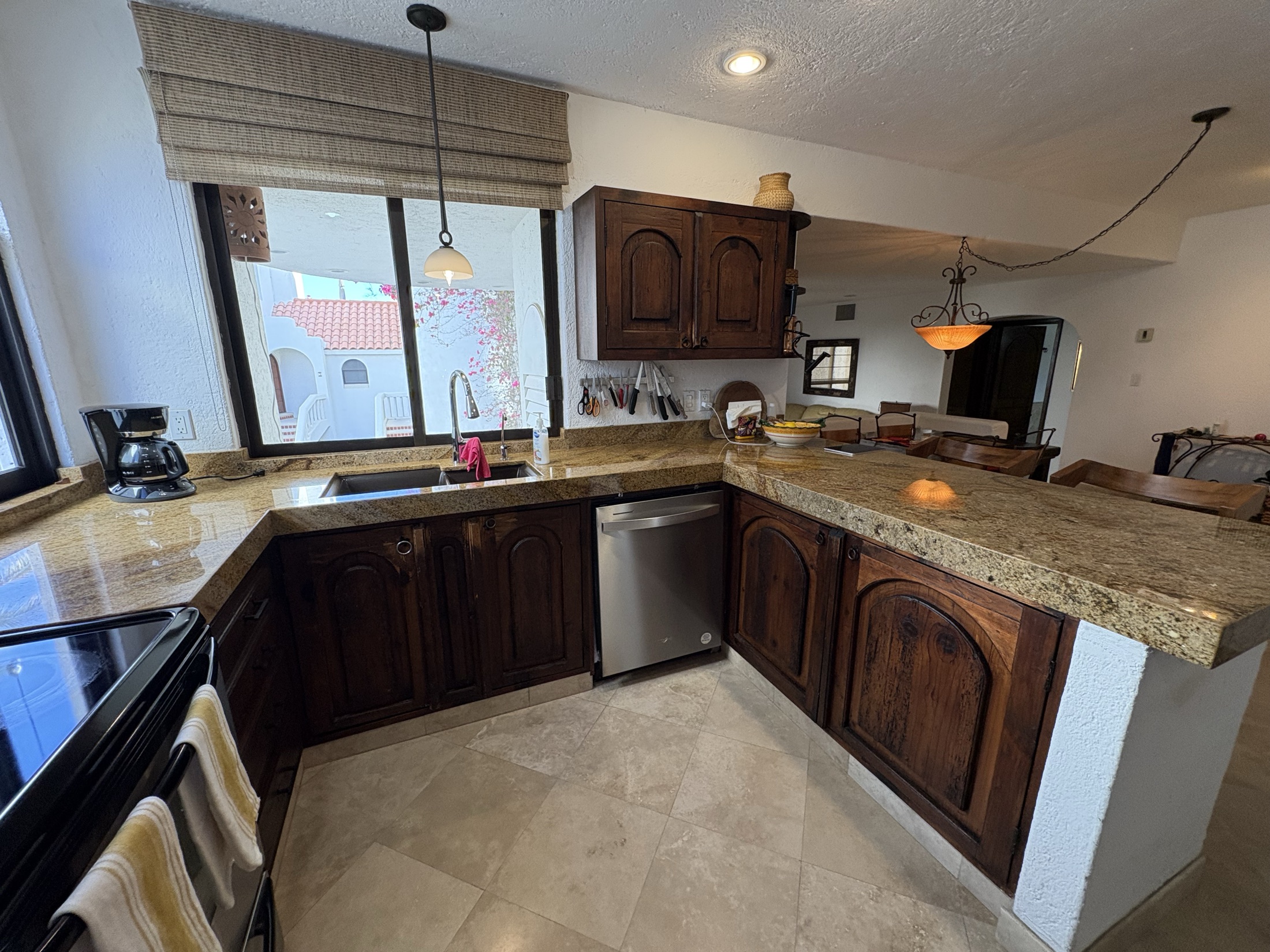 Kitchen counters with sink, window, dishwasher, and granite surfaces