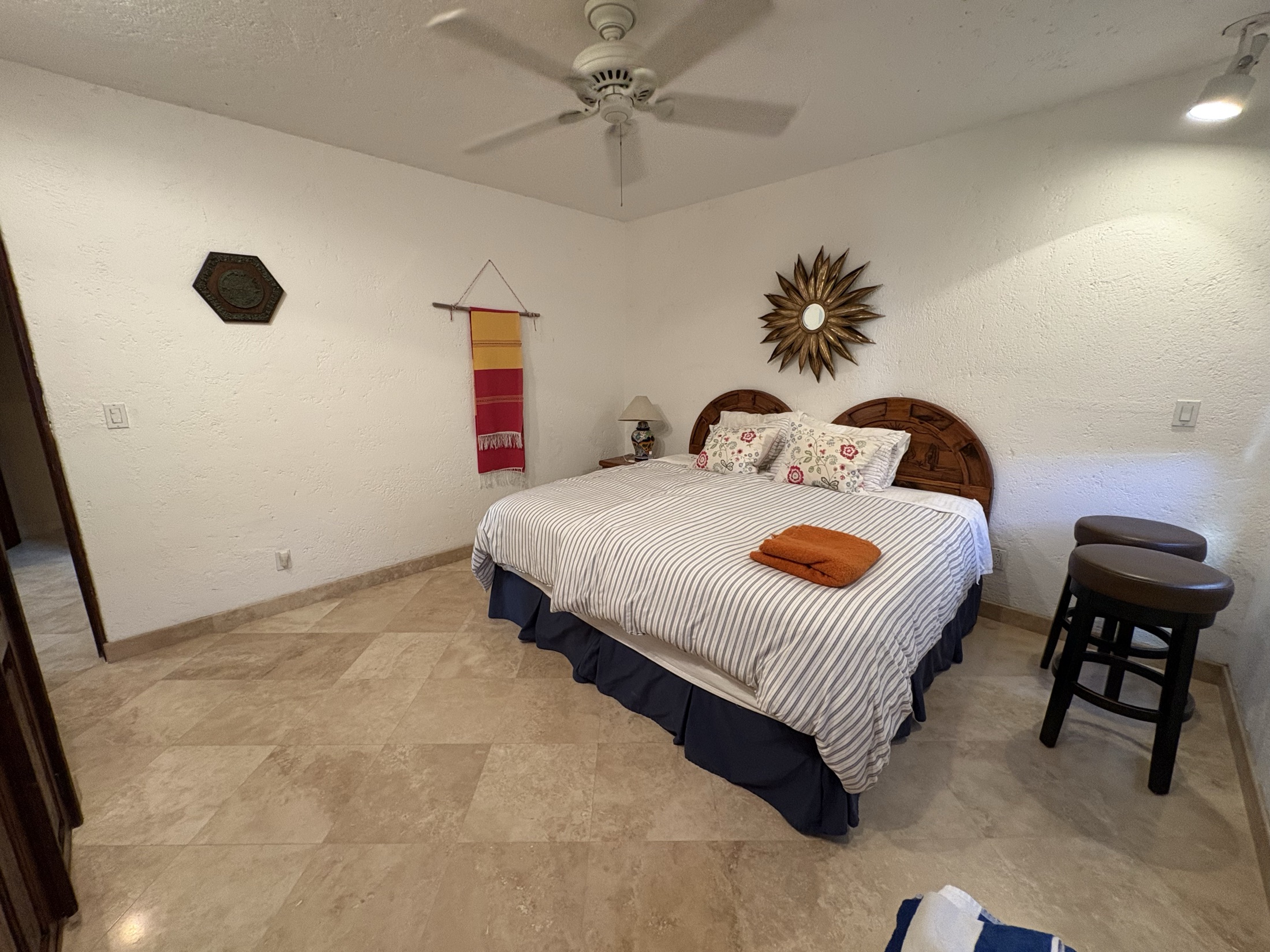 Primary bedroom with carved wood bed, travertine floors, and Tecno blinds